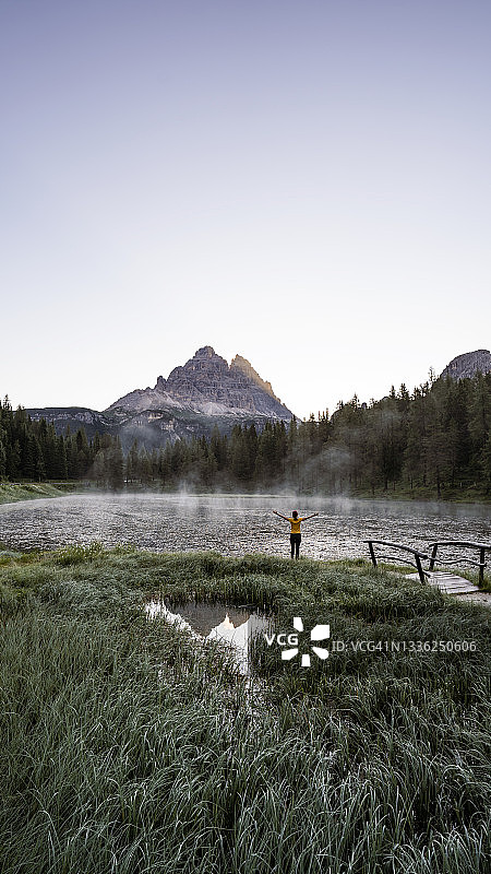 年轻女人在湖边码头上拥抱大自然放松身心图片素材