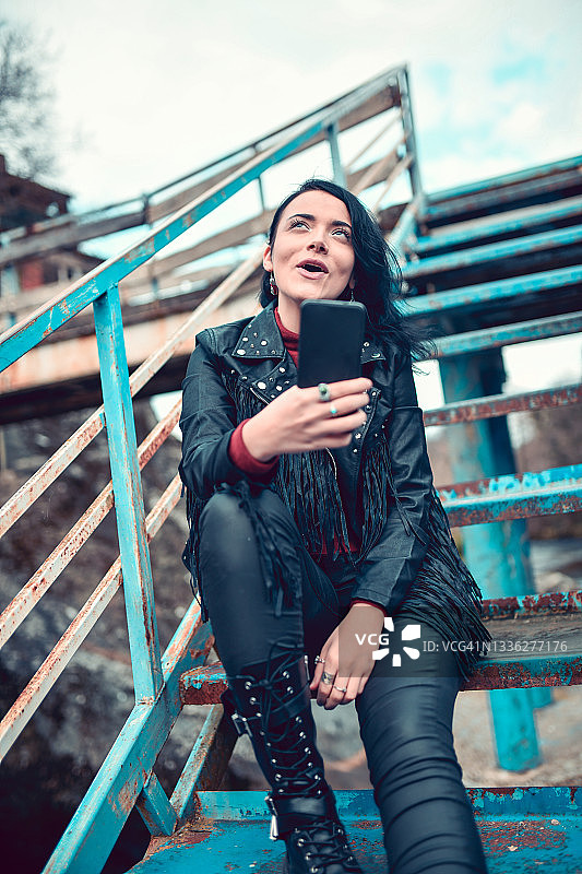 朋克摇滚风格的年轻女子在废弃的桥上自拍图片素材