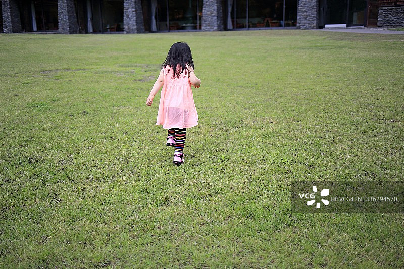 在草地上行走的小孩（背面视角）图片素材