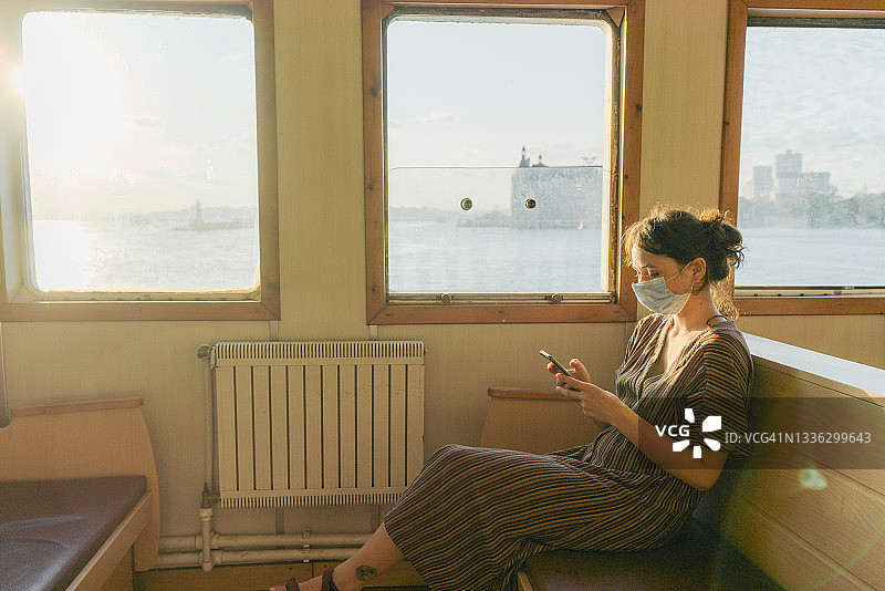在伊斯坦布尔博斯普鲁斯海峡的渡轮上使用智能手机的女人图片素材