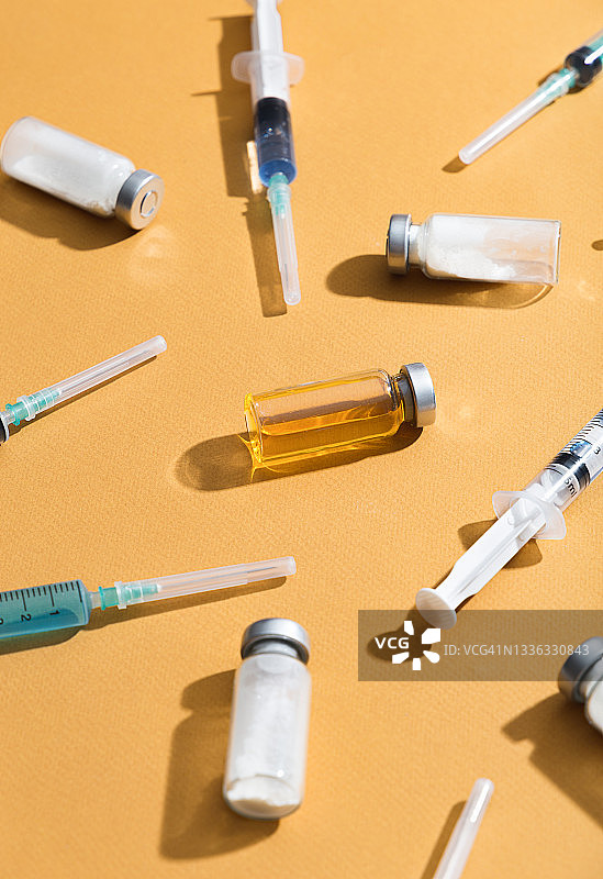 黄色背景上的注射器和医疗疫苗瓶图片素材