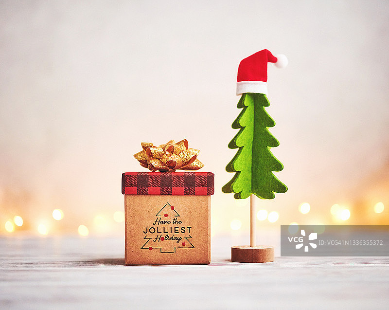 礼品盒上的带节日祝福和蝴蝶结的小圣诞树图片素材