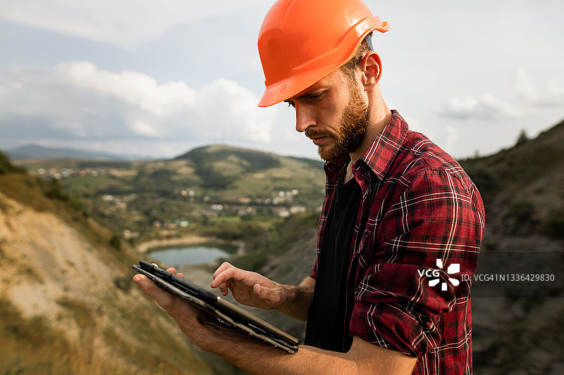 英俊的年轻男工程师在采石场使用平板电脑工作图片素材