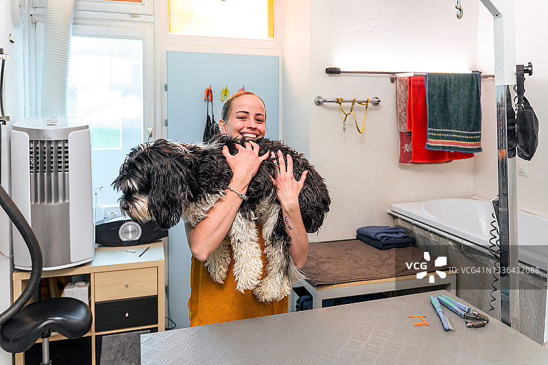年轻白人女性宠物店主抱着狗图片素材