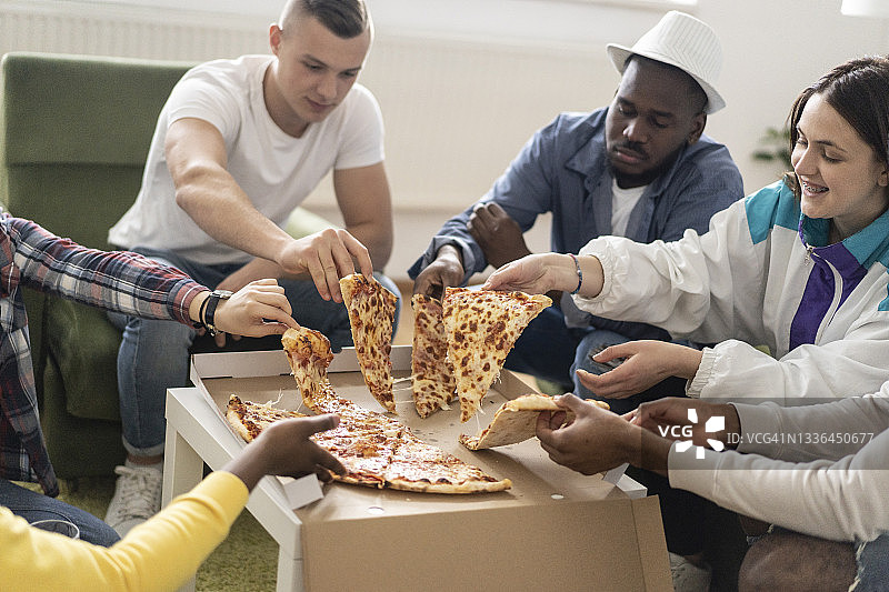 朋友们从外卖盒中拿起披萨图片素材