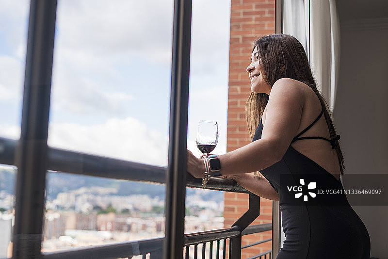 在房子里喝着葡萄酒的40岁拉丁女人图片素材