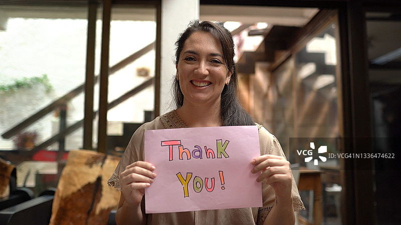 在家中手持写有“谢谢你”字样的纸张的女人图片素材