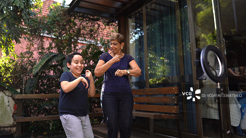 男孩和奶奶在家跳舞并拍摄图片素材