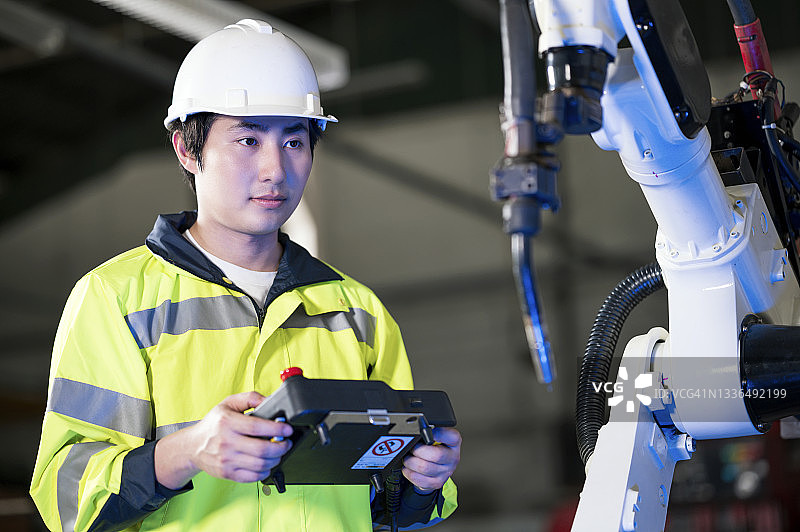 我们需要提高生产力。工程师在工厂的汽车零件生产线上操作和测试功能性工业机器人焊接。生产力和质量改进。制造业零浪费概念。图片素材
