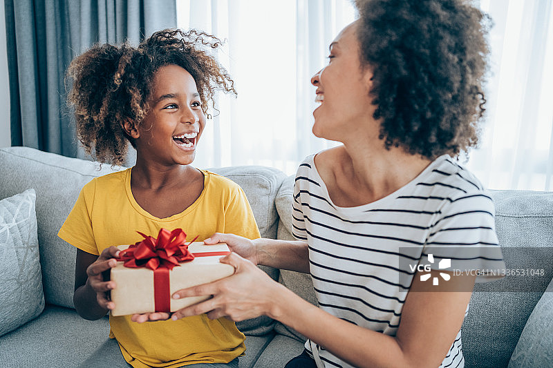 快乐的孩子收到妈妈的礼物。图片素材