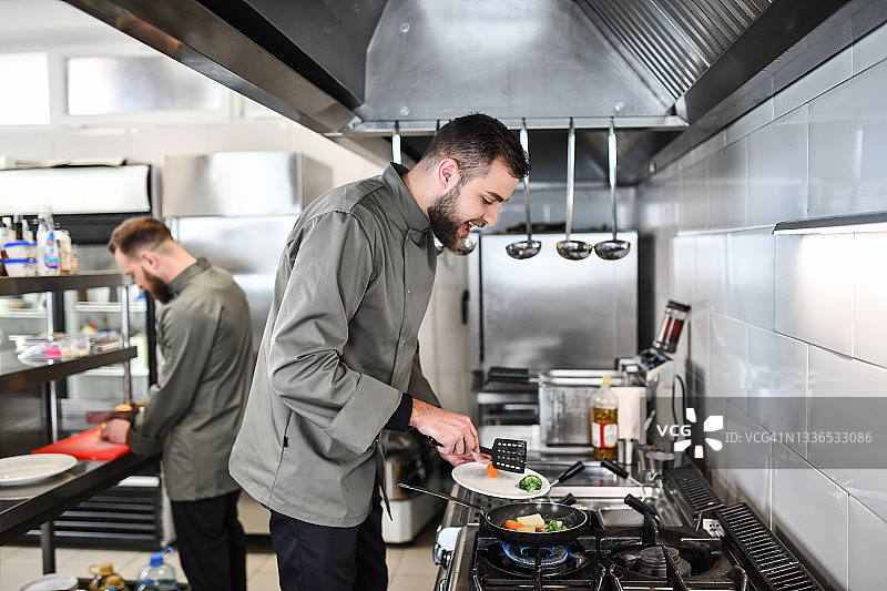 快乐的厨师在漂亮的餐厅厨房准备美食图片素材