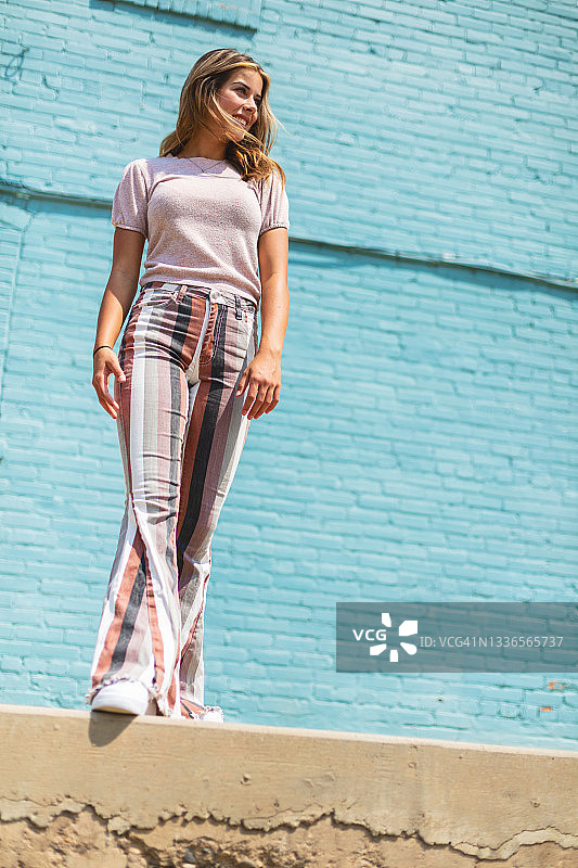 蓝色砖墙前的少女摄影图片素材