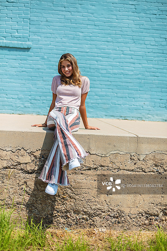 蓝色砖墙前的少女摄影图片素材