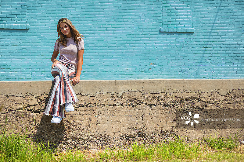 蓝色砖墙前的少女摄影图片素材