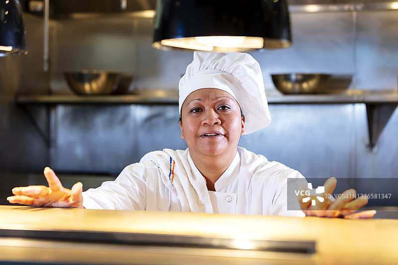 商业厨房柜台后的女厨师图片素材