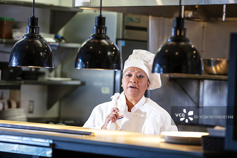 商业厨房柜台后的女厨师图片素材