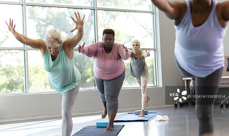 四个女人在练习瑜伽，呈战士三式图片素材