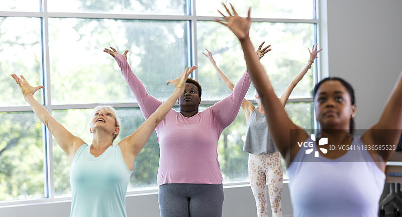 四个女人一起上瑜伽课，举起手臂图片素材