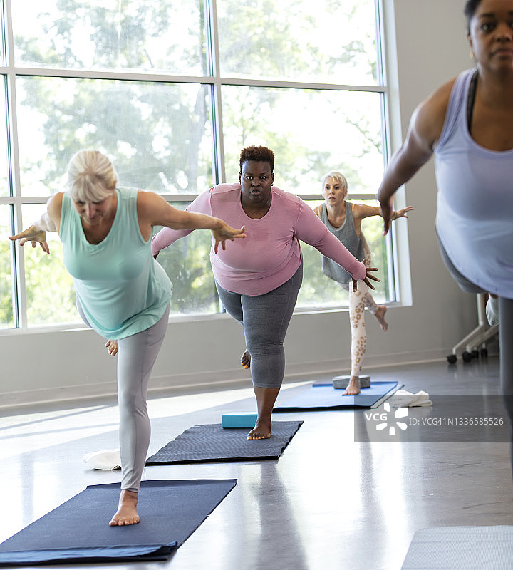 四个女人在练习瑜伽，呈战士三式图片素材