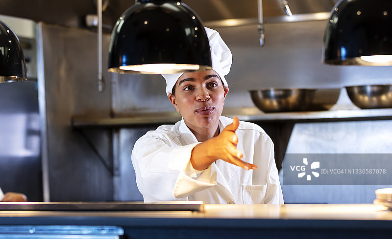 在厨房备餐台后方说话的女厨师图片素材