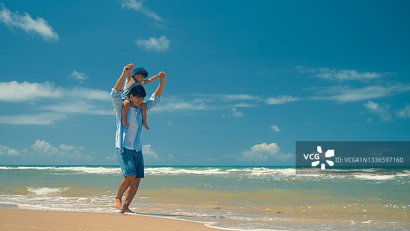 在海滩上的幸福家庭。人们在暑假玩得很开心。父亲、母亲和孩子以蓝色大海和天空为背景。假日旅行概念图片素材