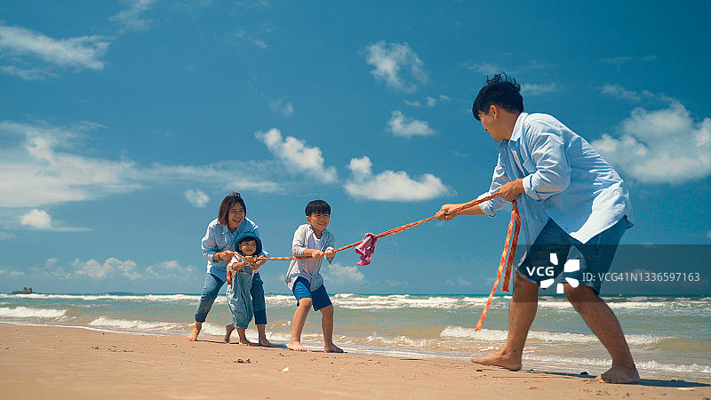 快乐的亚洲家庭在海滩上玩拔河游戏图片素材