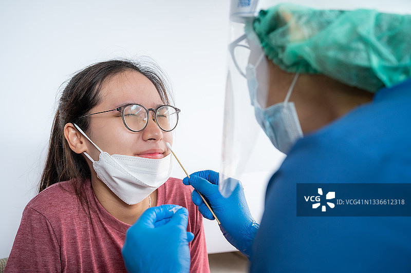 医护人员为亚洲女性进行新冠病毒检测的鼻拭子采样图片素材