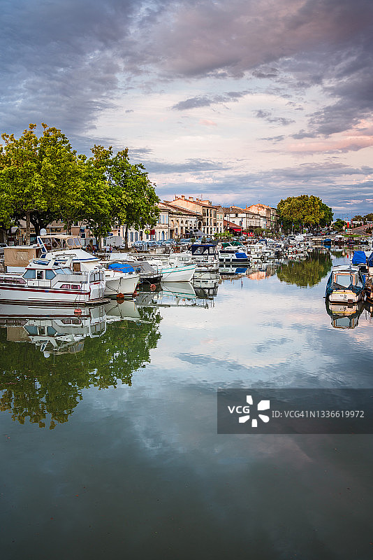 城市景观在静水中倒影的垂直视图，法国博凯尔罗纳河畔塞特运河图片素材