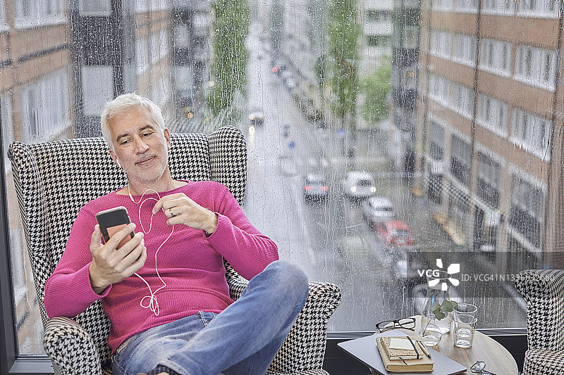 坐在扶手椅上用智能手机进行视频通话的男人图片素材
