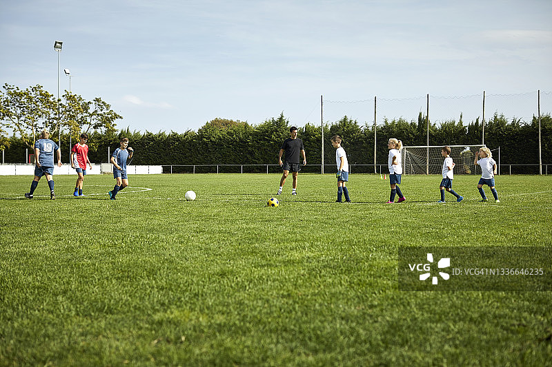教练在球场教孩子们踢足球图片素材