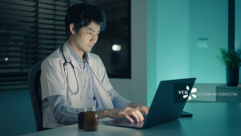 医生深夜在诊所使用笔记本电脑图片素材