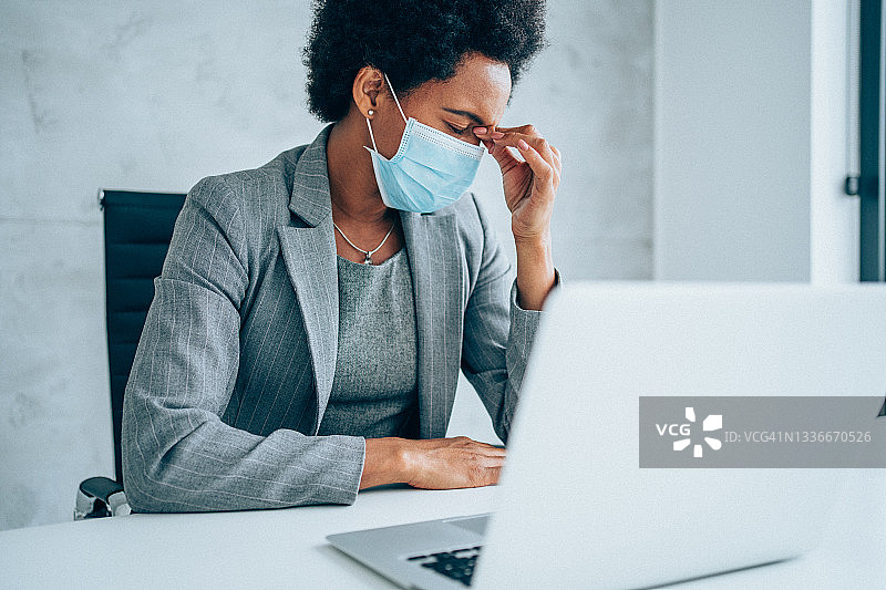 戴防护口罩，头痛的女商人图片素材