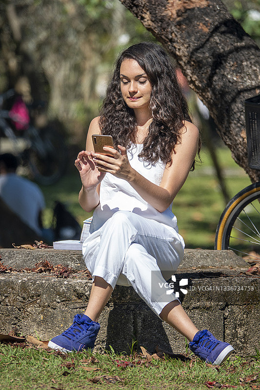 年轻女人在公园发短信图片素材