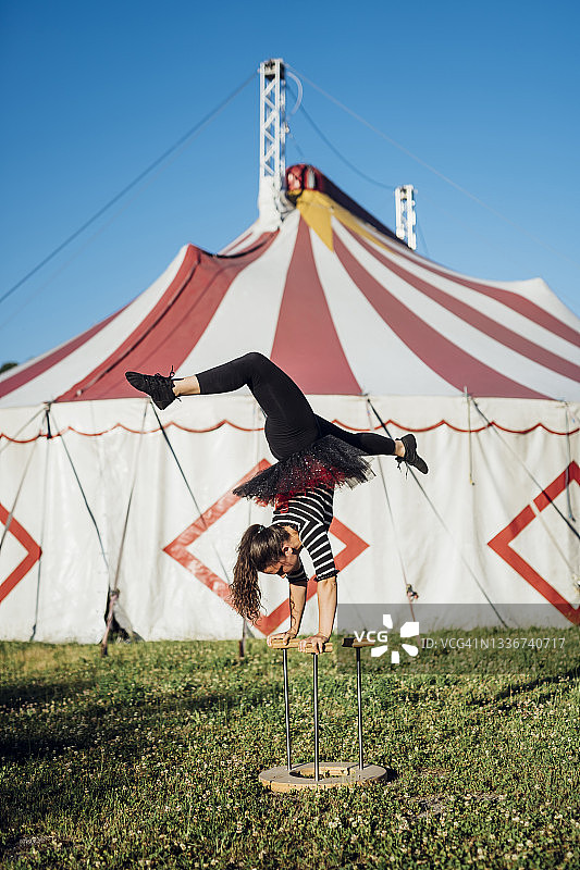 女杂技演员在马戏团帐篷前用手杖倒立图片素材