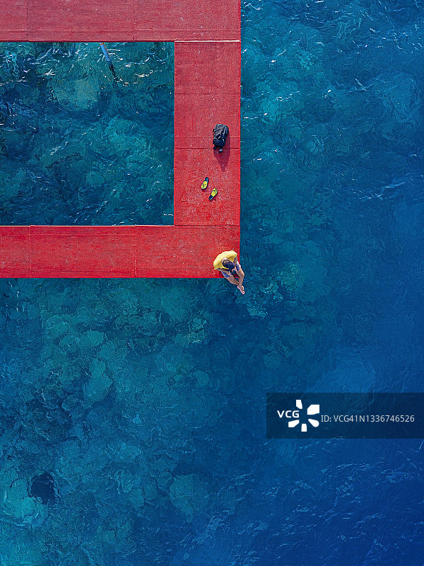 男人坐在马尔代夫卡夫环礁图卢斯杜岛的红色码头上，眺望大海图片素材