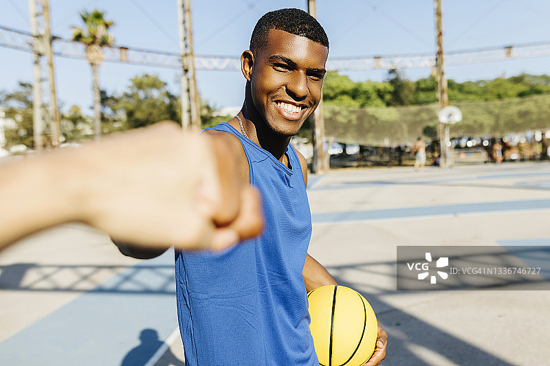 微笑的男人在运动场上与朋友碰拳图片素材