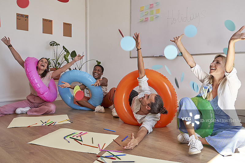 男女同事在办公室用充气泳圈庆祝节日图片素材