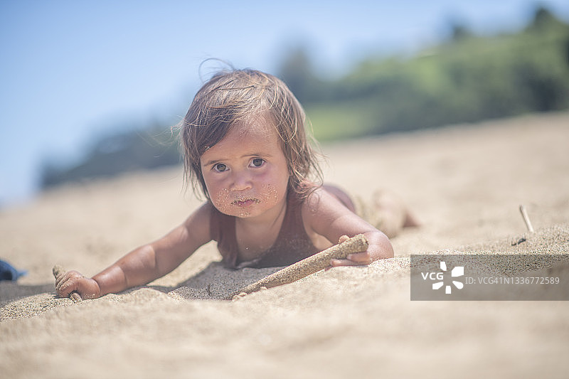 可爱的幼儿女孩躺在沙滩上图片素材
