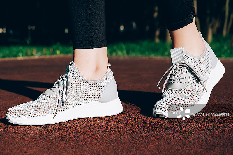 阳光下的运动场上的灰色女士运动鞋图片素材