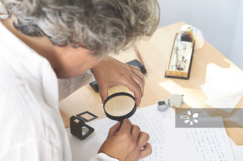 笔迹学家用放大镜分析信件，笔迹学概念图片素材
