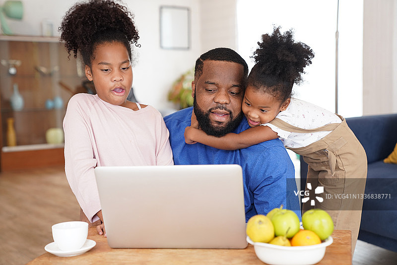 父亲在家工作，孩子们试图在笔记本电脑上打字图片素材