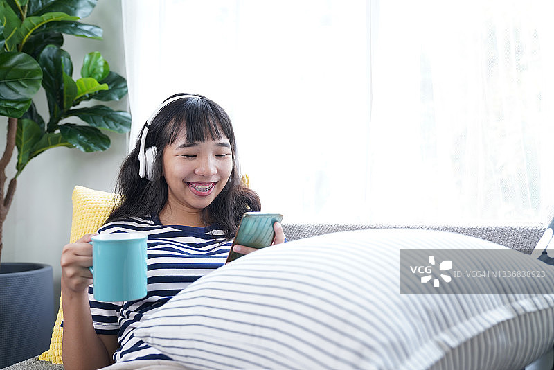 年轻女人在客厅放松时与朋友进行愉快的视频通话图片素材