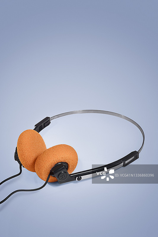 蓝色背景上的橙色耳罩80年代复古耳机图片素材