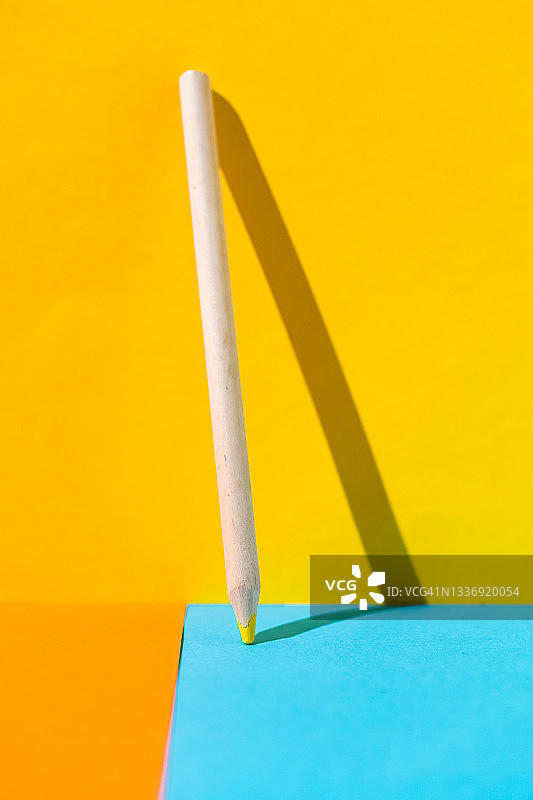 黄色木制铅笔靠在黄色墙壁和蓝橙色地板上，学校、办公室和文具概念图片素材