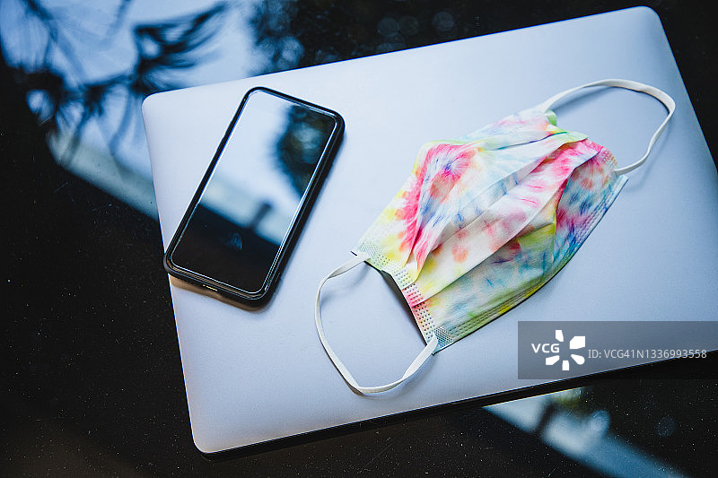 俯视视角：办公桌上的口罩、笔记本电脑和手机图片素材