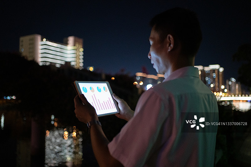 年轻的亚洲商人在夜晚使用平板电脑图片素材