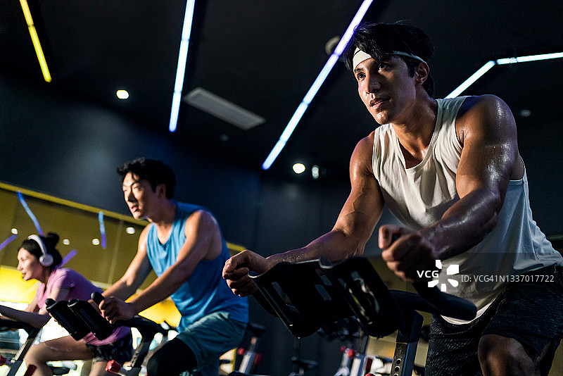 年轻人在健身房的室内自行车课上骑动感单车图片素材