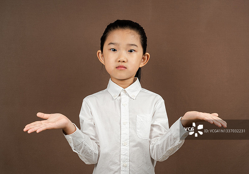 棕色背景上做出无助姿势的小女孩图片素材