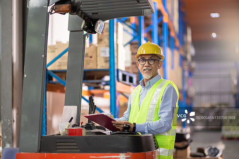 中国亚洲老年仓库工人操作叉车在工厂工作图片素材