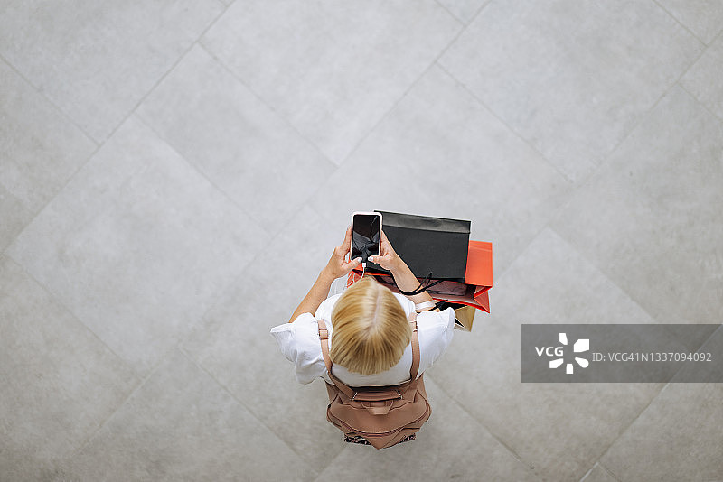 在购物中心使用手机的女士图片素材